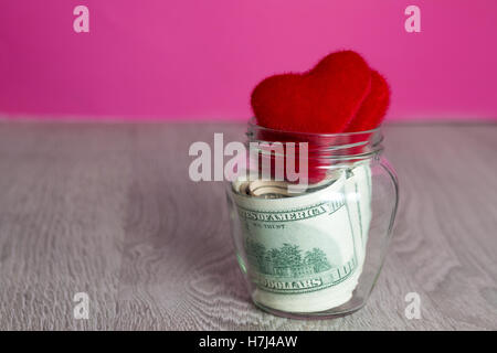 Geld und roten Herzen. Dollar in offenen Tiegels auf grauem Holz Textfreiraum. Liebe. Valentinstag. Stockfoto