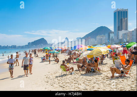 RIO DE JANEIRO - 27. Februar 2016: Massen der Strandbesucher füllen Copacabana-Strand mit bunten Sonnenschirmen am hellen Nachmittag. Stockfoto