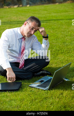 Geschäftsmann, sitzend in einem Park mit einem laptop Stockfoto