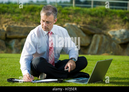 Geschäftsmann, sitzend in einem Park mit einem laptop Stockfoto