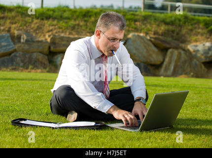 Geschäftsmann, sitzend in einem Park mit einem laptop Stockfoto