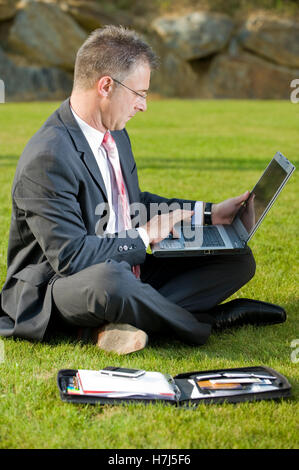Geschäftsmann, sitzend in einem Park mit einem laptop Stockfoto