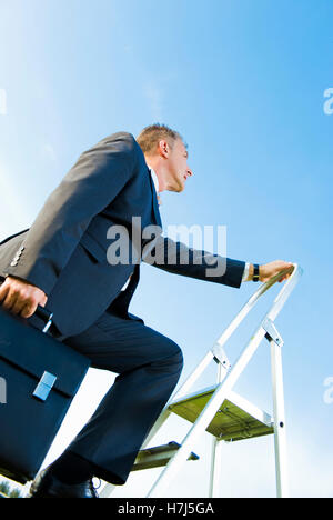 Geschäftsmann, Klettern, eine Leiter, ein symbolisches Bild für die Karriereleiter Stockfoto