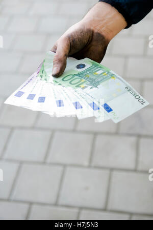 Symbolisches Bild von Schwarzgeld, manuelle Arbeiter mit schmutzigen Händen hält Banknoten Stockfoto