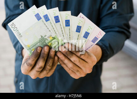 Symbolisches Bild von Schwarzgeld, manuelle Arbeiter mit schmutzigen Händen hält Banknoten Stockfoto