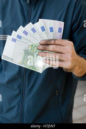 Symbolisches Bild von Schwarzgeld, manuelle Arbeiter mit schmutzigen Händen hält Banknoten Stockfoto