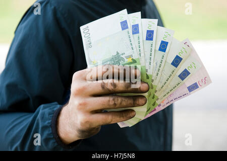 Symbolisches Bild von Schwarzgeld, manuelle Arbeiter mit schmutzigen Händen hält Banknoten Stockfoto