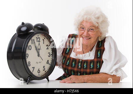 Es ist fast zwölf Uhr mittags, ältere Frau mit einem Wecker Stockfoto