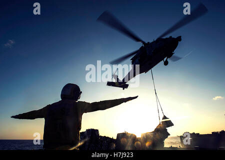 Ein US-Soldat signalisiert einen MH-60 Seahawk Hubschrauber Landung auf dem Flugdeck der USN Ticonderoga-Klasse geführte Flugkörper Kreuzer USS Chancellorsville 25. Oktober 2016 in der Philippinensee. Stockfoto