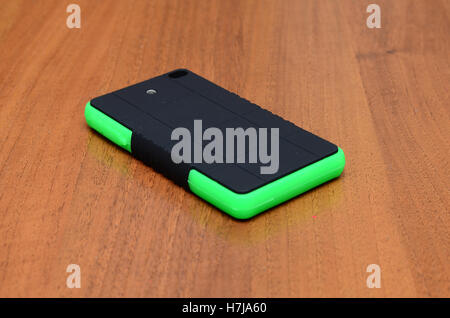 Hält ein intelligentes Telefon während des Ladevorgangs mit solar-Ladegerät in weißem Hintergrund Stockfoto