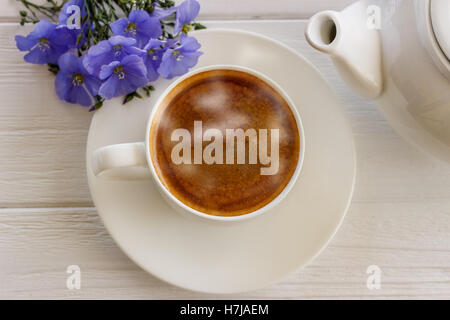 Kaffeebecher mit blauen Blüten und Notizen guten Morgen Frühstück am blauen rustikalen Tisch von oben, Stockfoto