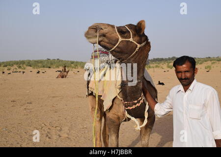 Indischer Mann mit seinem Kamel in der Wüste Thar nahe Jaisalmer, Rajasthan, Indien