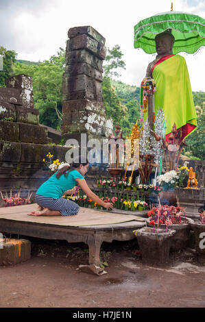 Ein Anhänger legt Blumen an Wat Phu, eine ruinierte Khmer Hindu Tempelanlage in Champasak im Süden von Laos. Stockfoto