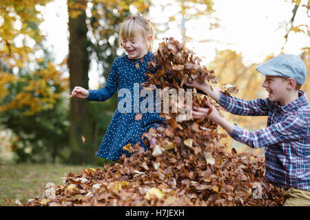 Happy Herbst. Zwei Kinder spielen in trockene Blätter Haufen im Herbst Park. Stockfoto