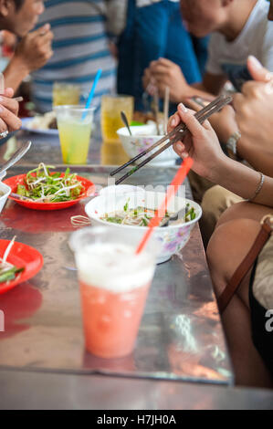 Gäste im Bürgersteig diner Bun Mam Dac San essen Bun Mam, Stechendem fermentiertem Fisch Suppe und einem Südvietnamesischen Delikatesse in Saigon. Stockfoto