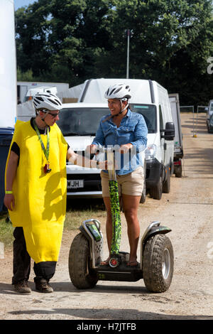 Junge Frau versucht zu reiten ein Zweirad aufstehen Elektroroller zum ersten Mal, Musikfestival, Jimmys Farm, Ipswich, UK Stockfoto