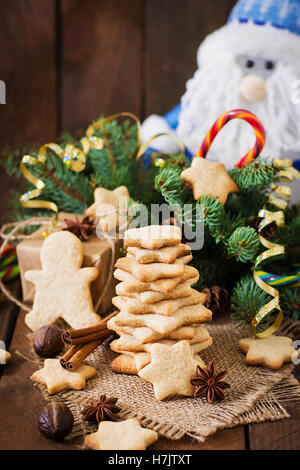 Weihnachtsplätzchen und Lametta auf dunklem Untergrund aus Holz Stockfoto