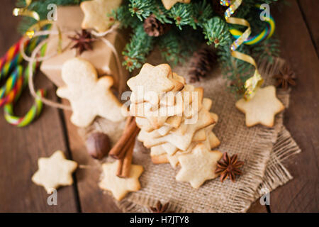 Weihnachtsplätzchen und Lametta auf dunklem Untergrund aus Holz Stockfoto