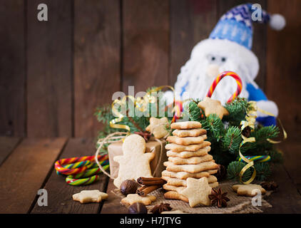 Weihnachtsplätzchen und Lametta auf dunklem Untergrund aus Holz Stockfoto