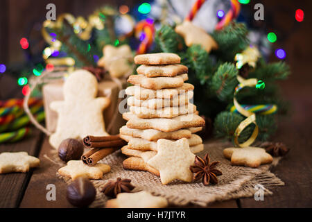 Weihnachtsplätzchen und Lametta auf dunklem Untergrund aus Holz Stockfoto