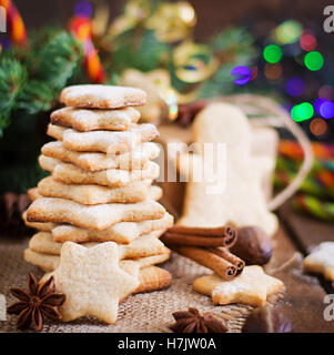 Weihnachtsplätzchen und Lametta auf dunklem Untergrund aus Holz Stockfoto