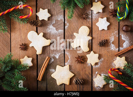 Weihnachtsplätzchen und Lametta auf einem dunklen Hintergrund aus Holz. Ansicht von oben Stockfoto