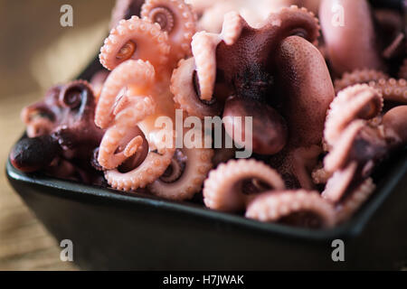 Gekochte kleine Krake auf einer schwarzen Platte Stockfoto