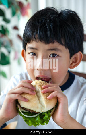 Asiatische junge auf seinem Burger zum Anbeißen. Stockfoto