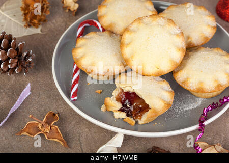 Sechs vergoldete Mince Pies auf eine festliche Weihnachten Tabelle mit Biss und aus dem einen von Ihnen getroffen Stockfoto