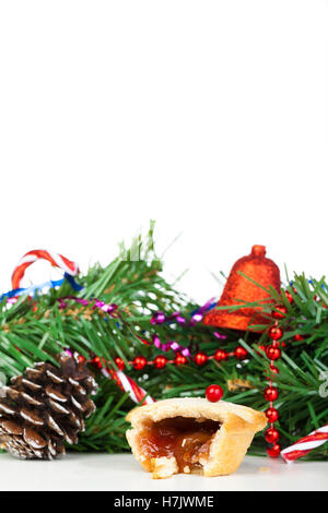 Porträtaufnahme der einen Hälfte gegessen Mince Pie und Weihnachts-Dekorationen auf weißem Hintergrund Stockfoto