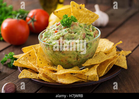 Guacamole Avocado, Limetten, Tomaten, Zwiebeln und Koriander, serviert mit Nachos - traditionelle mexikanische Snack. Stockfoto