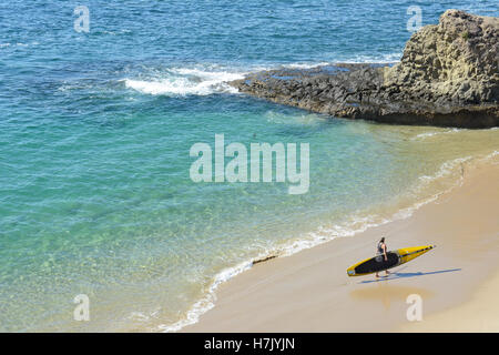 Ein unbekannter Mann mit seinem Kajak entlang der Küste in Laguna Beach, Kalifornien. Stockfoto