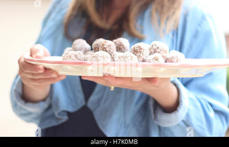 Frau hält einen Teller mit Schokoladen-Trüffel / rum Kugeln Stockfoto