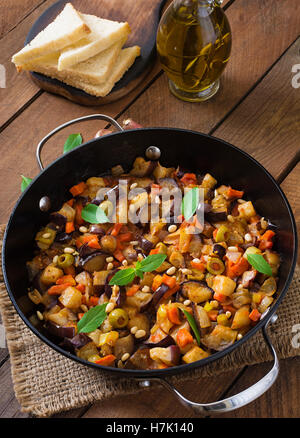 Italienische Caponata mit Pfanne auf einem hölzernen Hintergrund. Stockfoto