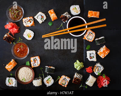 Traditionelles japanisches Essen - Sushi, Brötchen und Sauce auf einem dunklen Hintergrund. Ansicht von oben Stockfoto