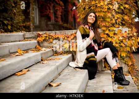 Junge Frau sitzt auf der Treppe draußen in Herbsttag Stockfoto