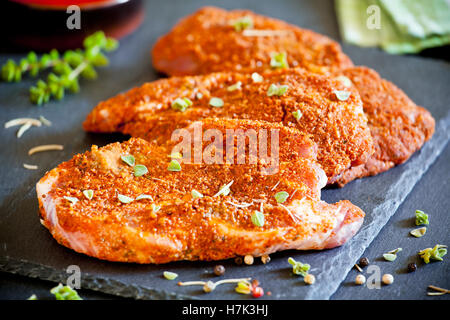 Drei marinierte Schweinekoteletts auf einer Schiefertafel Platte Stockfoto