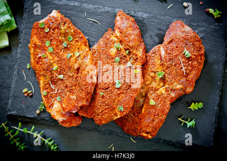 Drei marinierte Schweinekoteletts auf einer Schiefertafel Platte Stockfoto