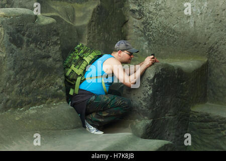 fotografiert Man zwischen Felsen in eine halb sitzende position Stockfoto