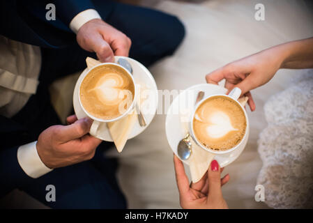 Einige Leute halten Tassen mit Caffee mit spät Kunst im Café Stockfoto