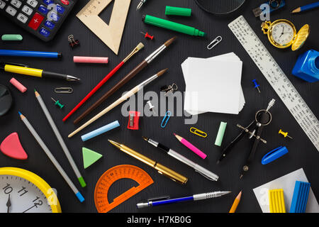 Schulmaterial auf schwarzem Hintergrund aus Holz Stockfoto