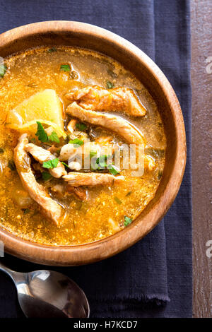 Hausgemachte Winter traditionelle Fleischsuppe mit Gemüse und Getreide in Holzschale über rustikalen Tisch hautnah Stockfoto
