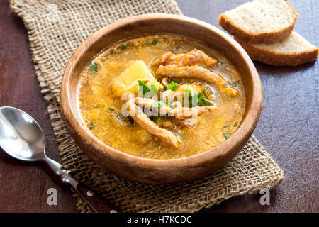 Hausgemachte Winter traditionelle Fleischsuppe mit Gemüse und Getreide in Holzschale über rustikalen Tisch Stockfoto