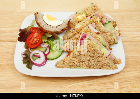 Schinken-Salat-Sandwiches mit Salat und ein Scotch-Ei auf einem Teller auf einer hölzernen Tischplatte Stockfoto
