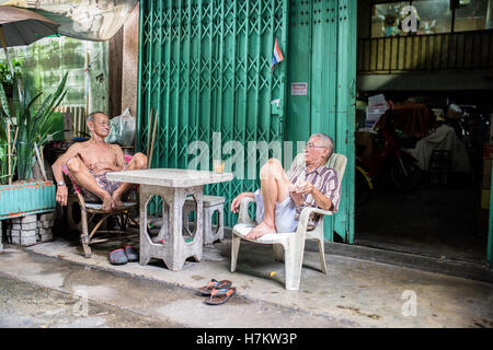 Zwei ältere Männer sitzen vor dem Haus in Bangkok Stockfoto