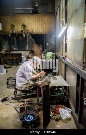 Ein Alter Mann Löten einige Sachen im Ladengeschäft Bangkok Stockfoto