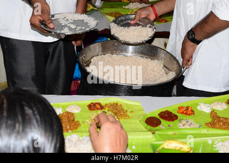 Traditionelle Sadhya, die Speisenausgabe in Banane Blätter mit Vielzahl von Currys Essen Server dienen Reis auf Bananenblatt Kerala Küche Stockfoto