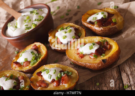 Gebackene Kartoffelschalen mit Käse, Speck und Sauerrahm-close-up auf dem Tisch. Horizontale Stockfoto