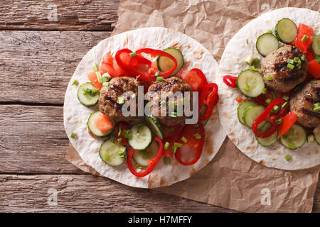 Gegrillte Frikadellen mit frischem Gemüse auf ein flaches Brot auf dem Tisch. horizontale Ansicht von oben Stockfoto