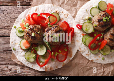 Gegrillte Frikadellen mit frischem Gemüse auf ein flaches Brot hautnah auf dem Tisch. horizontale Ansicht von oben Stockfoto